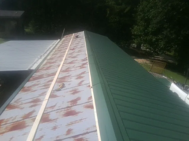 Old rusted panels beside newly installed green metal roofing — Wind Damage Roof Repair by Roofing Brothers in Algonquin