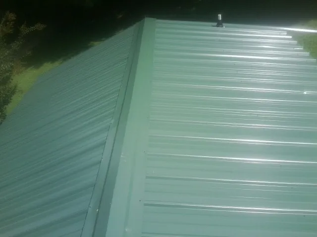 New green metal panels meeting at the ridge of a roof — Flat Roof Repair work by our crew in Algonquin