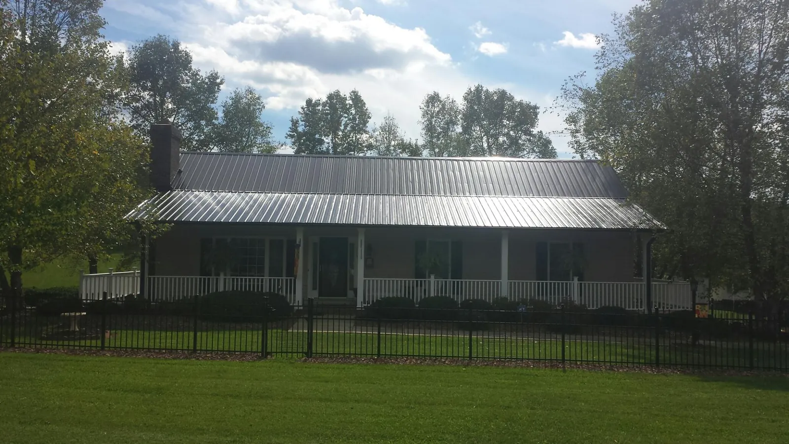 Gray metal roof on a brick ranch with a full width front porch — Gutter Guard Installation work by our crew in Algonquin