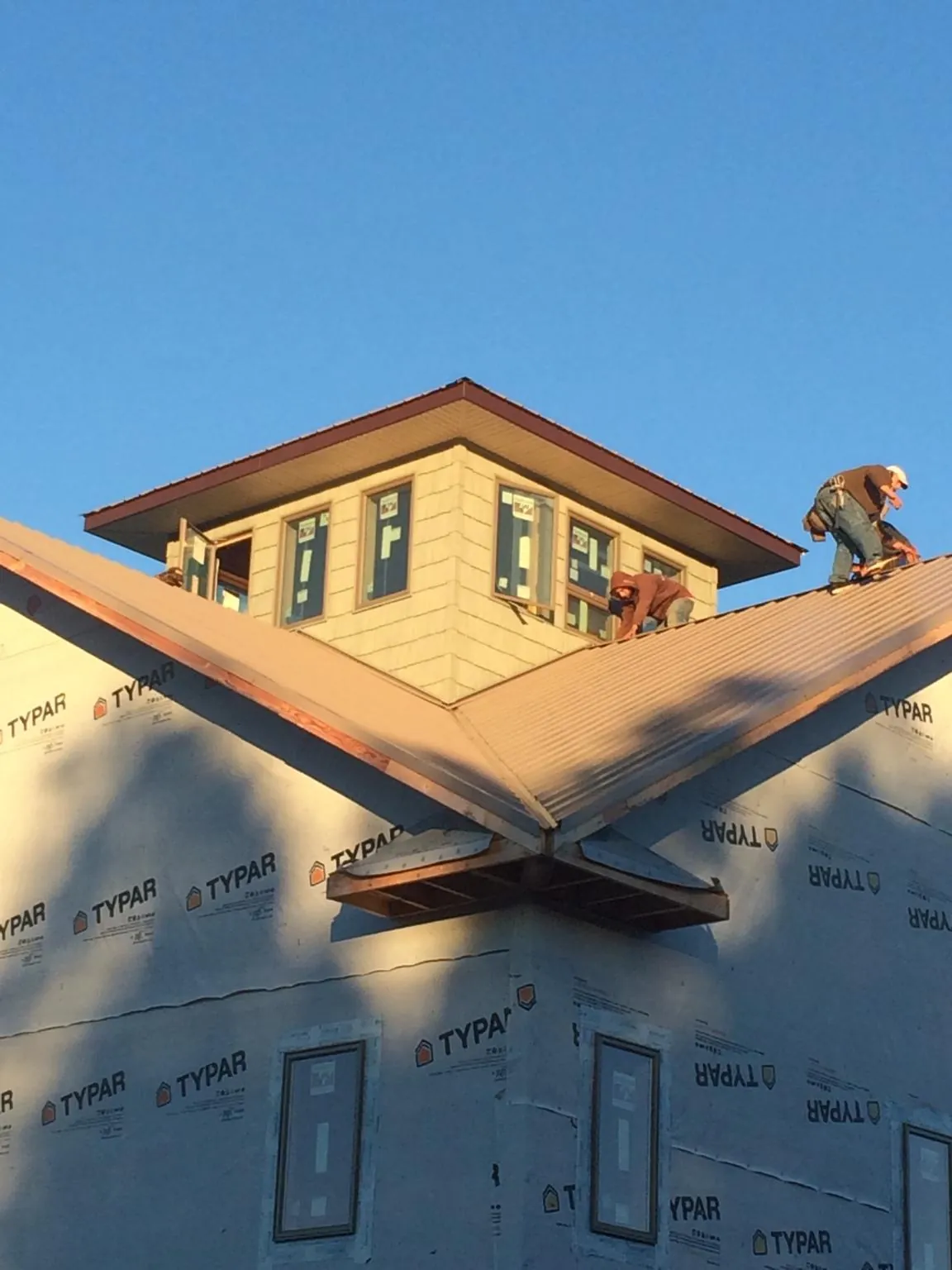 Roofers working around a rooftop cupola on a new metal roof at sunset — Roof Waterproofing in Algonquin by Roofing Brothers